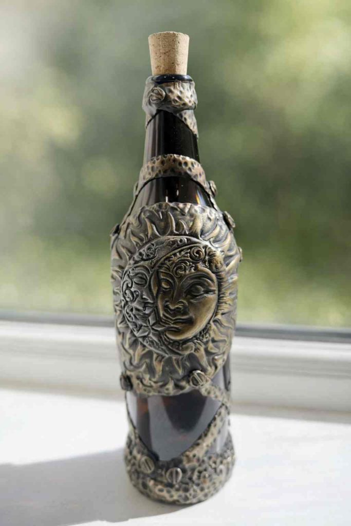 Brown beer bottle dressed in silver and gold polymer clay with sun and moon motiff